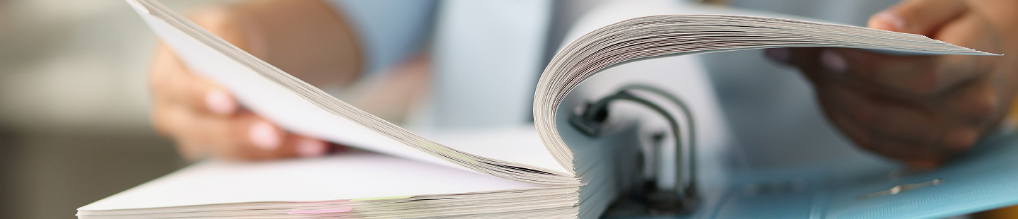 Eine Person blättert durch einen Ordner mit mehreren unbeschrifteten Blättern.