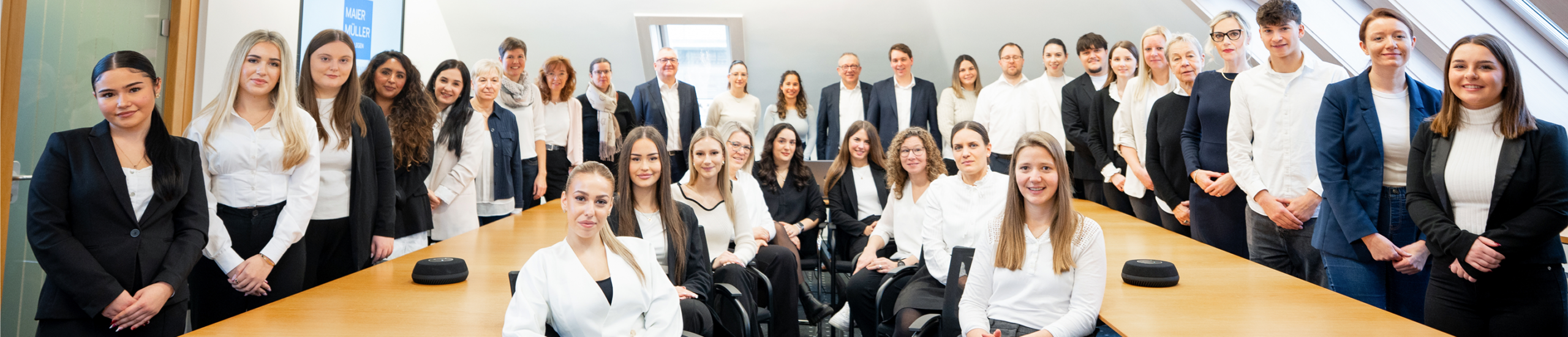 Gruppenfoto in einem Konferenzraum mit mehreren Personen in formeller Kleidung, die lächeln und posieren.